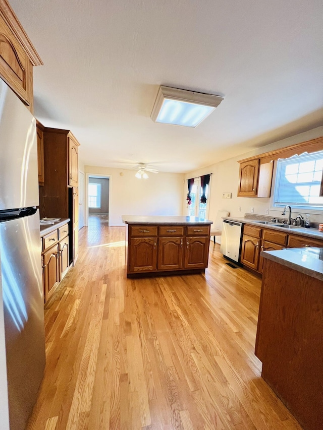 kitchen featuring light wood finished floors, plenty of natural light, appliances with stainless steel finishes, and a sink