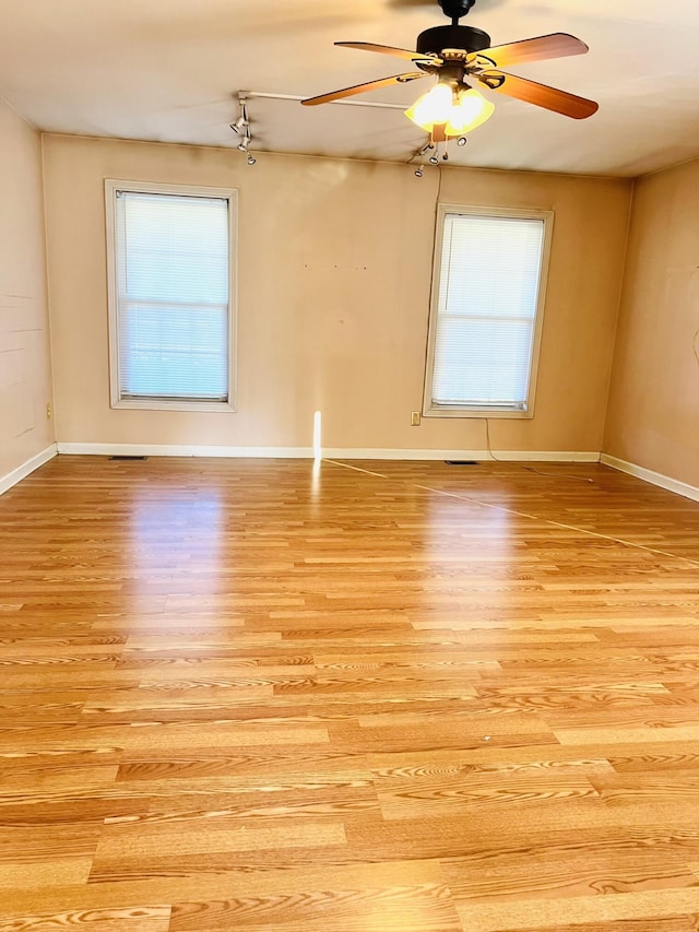 spare room featuring baseboards, ceiling fan, and light wood-style floors