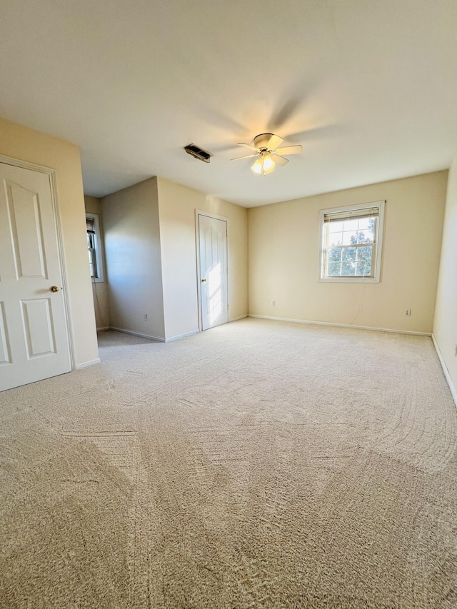 carpeted empty room with ceiling fan, visible vents, and baseboards