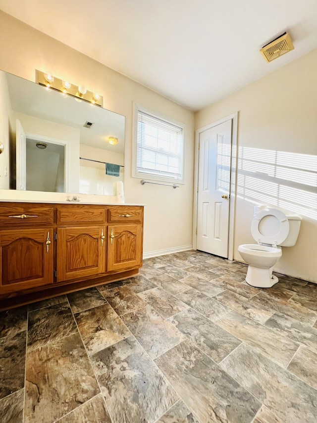 bathroom featuring baseboards, visible vents, vanity, and toilet