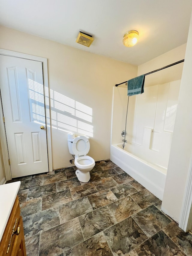 bathroom featuring toilet, vanity, visible vents, shower / washtub combination, and stone finish flooring