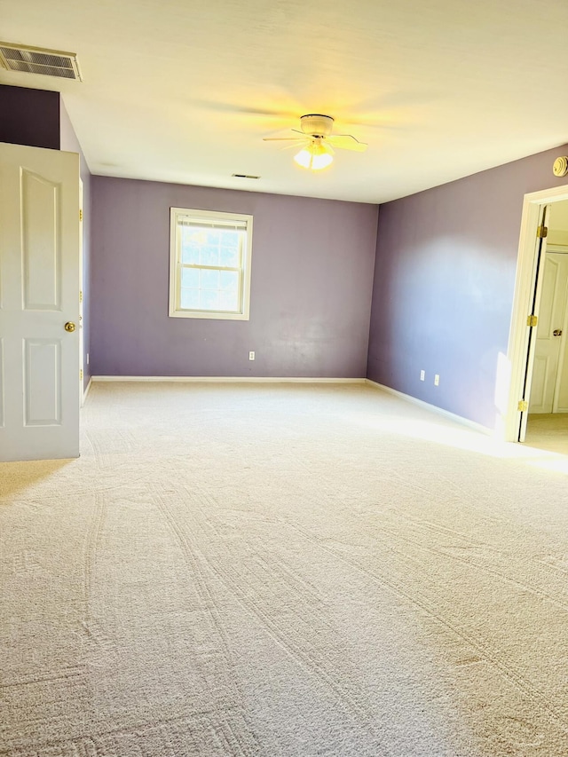 empty room with carpet flooring, visible vents, and baseboards