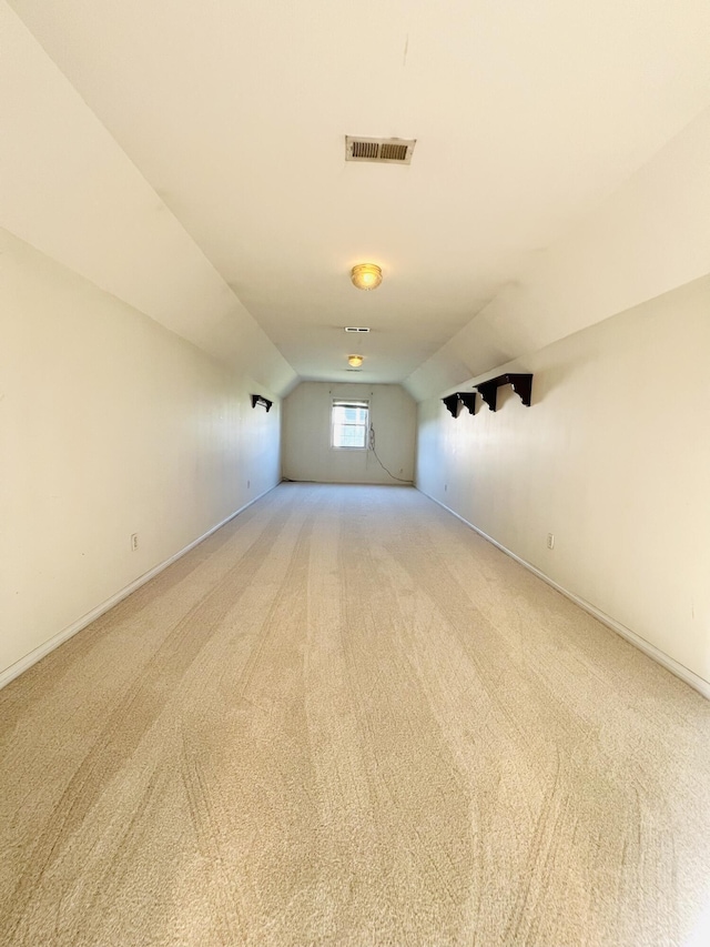 additional living space with lofted ceiling, light colored carpet, visible vents, and baseboards