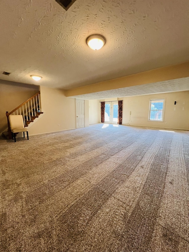 interior space with stairs, baseboards, and a textured ceiling