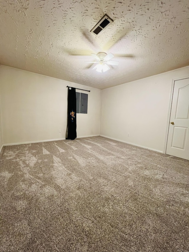 carpeted empty room featuring a textured ceiling, visible vents, and baseboards