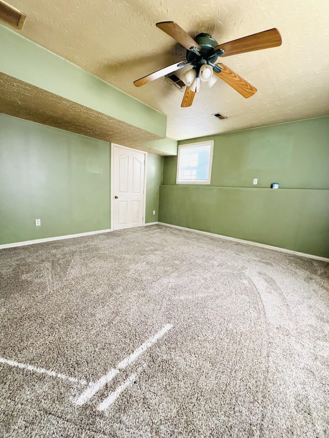 carpeted spare room with a ceiling fan, baseboards, visible vents, and a textured ceiling