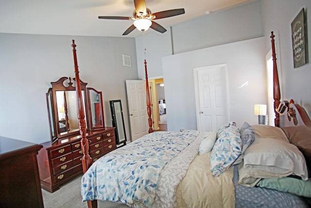 carpeted bedroom with ceiling fan and high vaulted ceiling