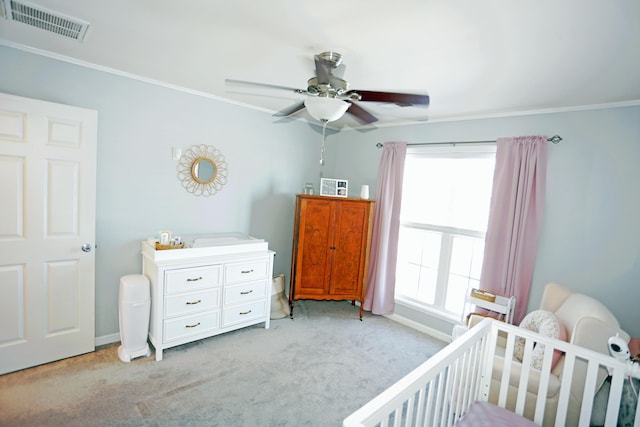 bedroom featuring crown molding, a crib, light colored carpet, and ceiling fan