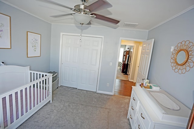 bedroom featuring ornamental molding, light carpet, ceiling fan, and a closet