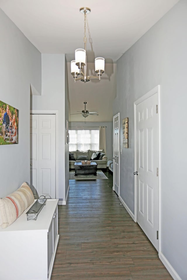 hall with dark hardwood / wood-style flooring, a notable chandelier, and a towering ceiling