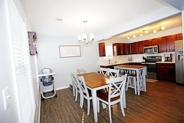 dining space with dark hardwood / wood-style flooring, a chandelier, and sink