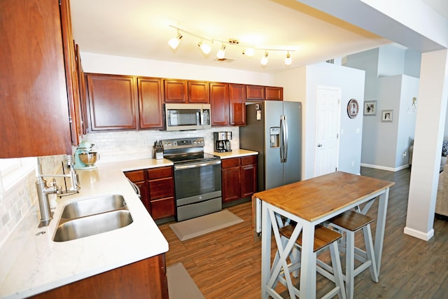 kitchen with tasteful backsplash, sink, dark wood-type flooring, and appliances with stainless steel finishes