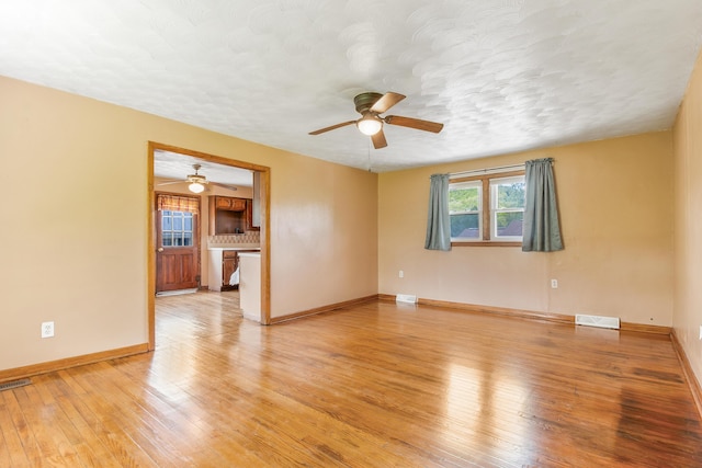 empty room with light wood-type flooring, ceiling fan, and a textured ceiling