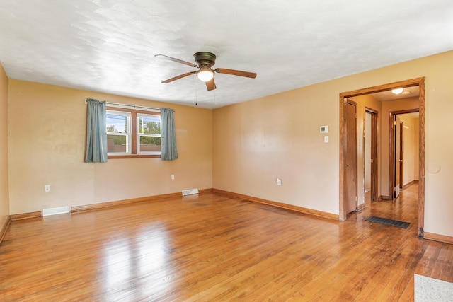 empty room with ceiling fan and light hardwood / wood-style flooring