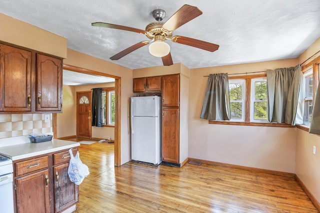 kitchen featuring light hardwood / wood-style floors, ceiling fan, white fridge, and a textured ceiling