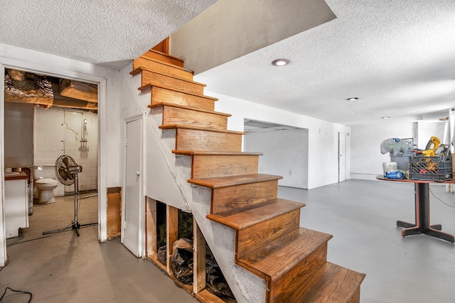 stairway with concrete flooring and a textured ceiling