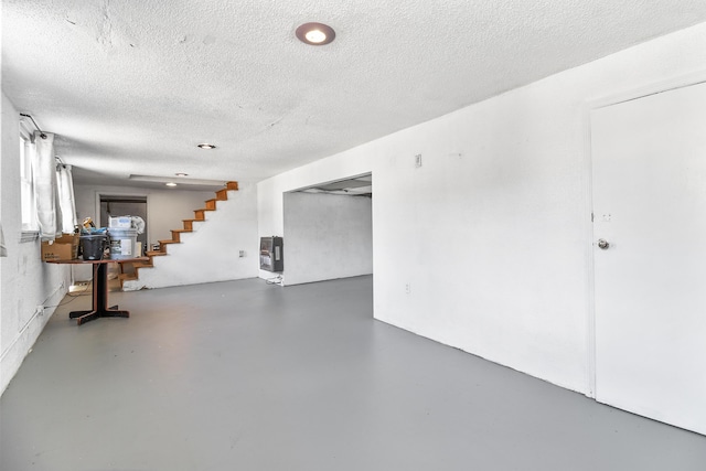 basement featuring a textured ceiling and heating unit