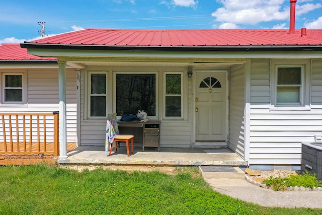 view of exterior entry featuring central AC unit and a porch