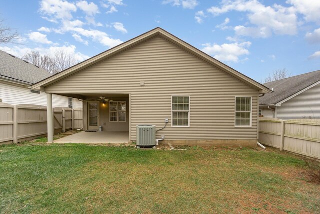 rear view of house with cooling unit, ceiling fan, a patio, and a lawn