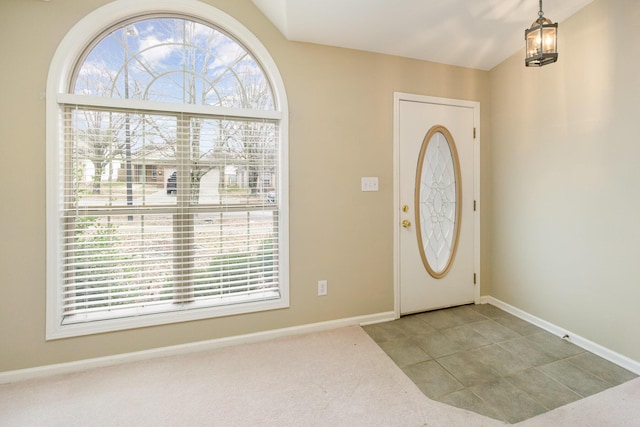 carpeted entryway featuring plenty of natural light, lofted ceiling, and an inviting chandelier