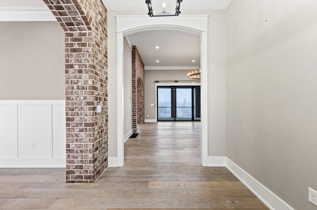 corridor featuring light hardwood / wood-style flooring, crown molding, and a notable chandelier