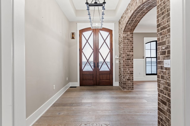 foyer entrance featuring hardwood / wood-style flooring, a tray ceiling, and french doors