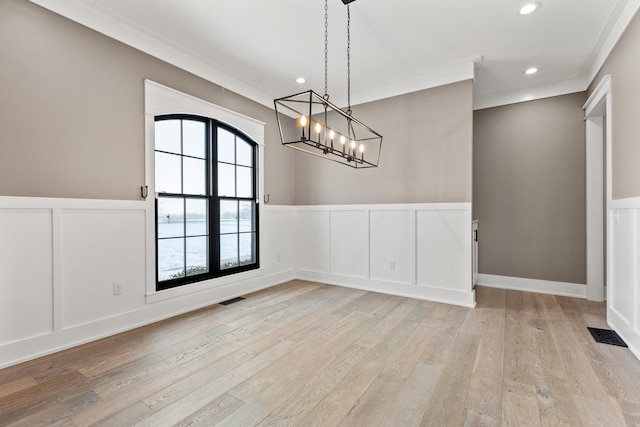 unfurnished dining area featuring light wood-type flooring and ornamental molding