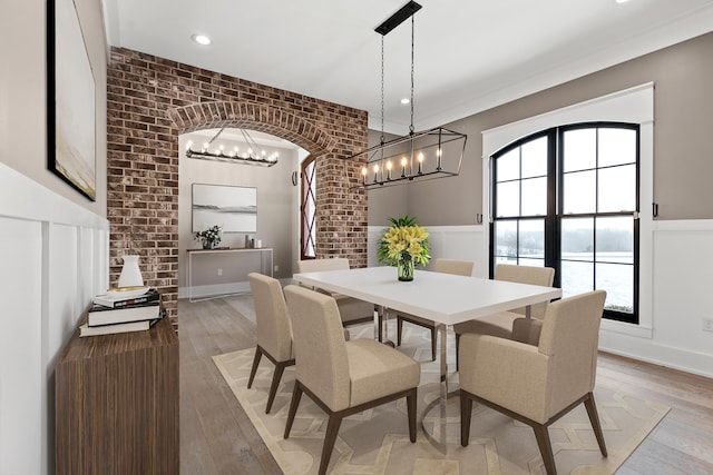 dining space featuring brick wall and light hardwood / wood-style flooring