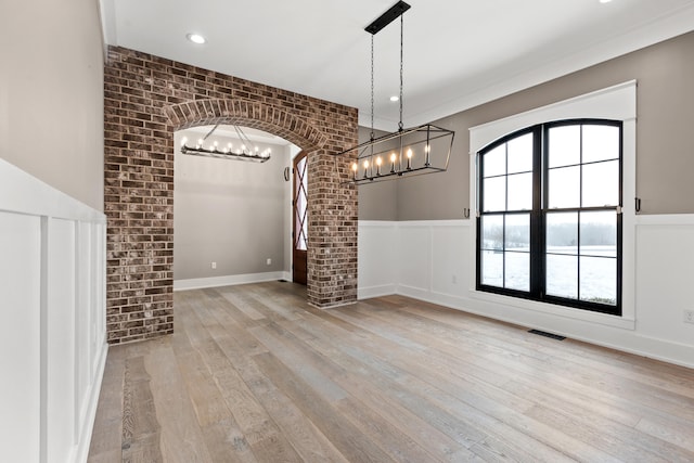 unfurnished dining area featuring light wood-type flooring and brick wall