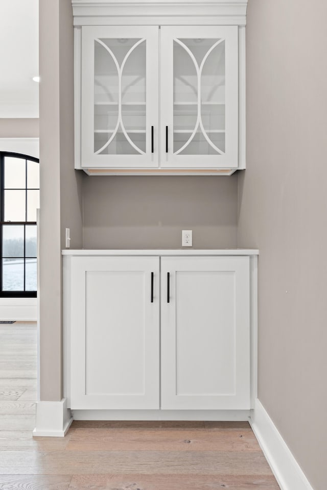 bar featuring white cabinets and light hardwood / wood-style flooring