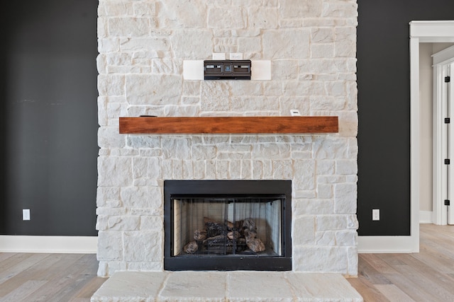 interior details featuring wood-type flooring and a stone fireplace