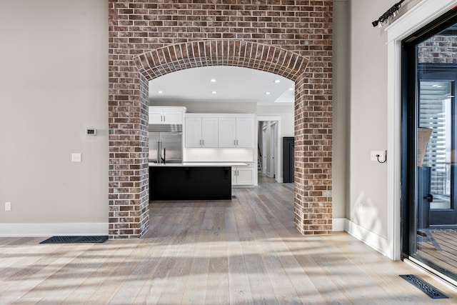 kitchen featuring stainless steel built in fridge, light wood-type flooring, white cabinetry, and a kitchen island