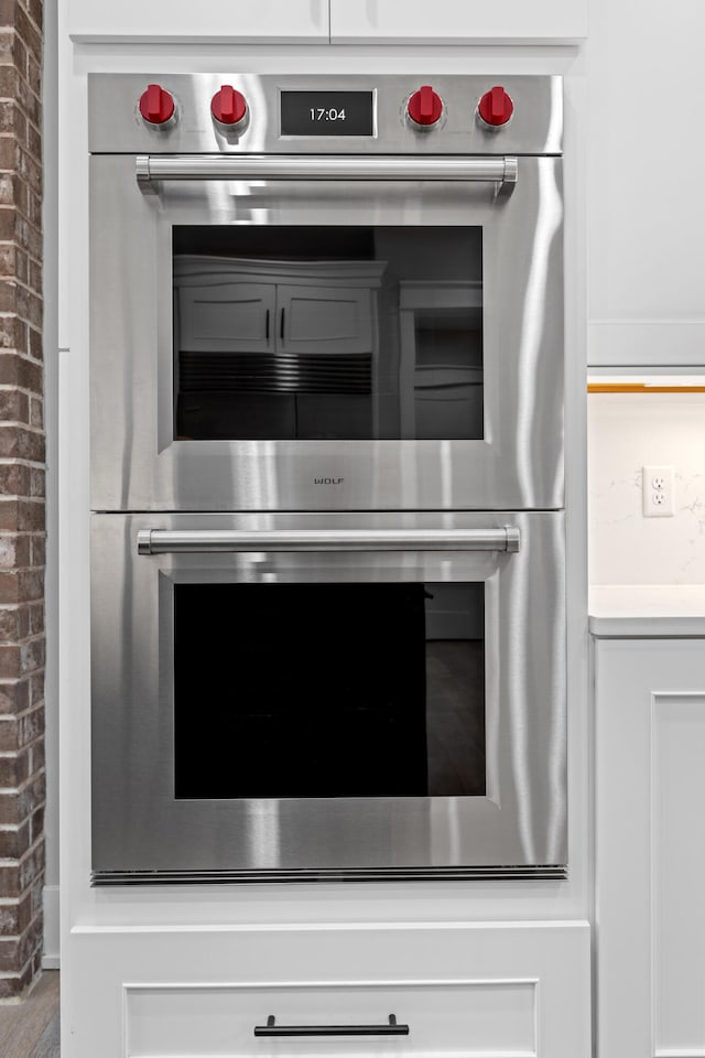 details featuring white cabinets and double oven