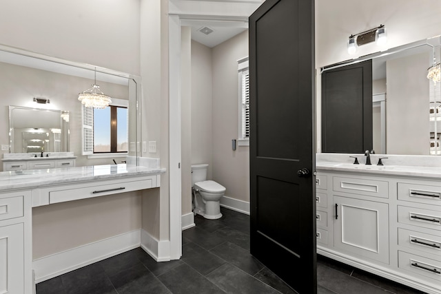 bathroom with vanity, toilet, a chandelier, and tile patterned floors