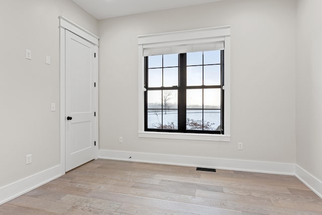 unfurnished room with light wood-type flooring and a water view