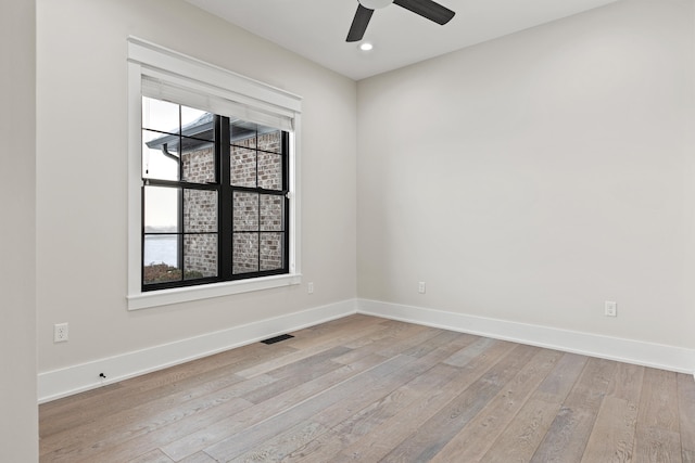 empty room with ceiling fan and light hardwood / wood-style flooring