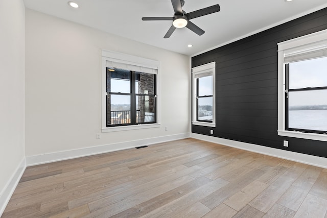 unfurnished room with ceiling fan, wood walls, light hardwood / wood-style flooring, and plenty of natural light