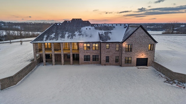 snow covered house featuring a garage