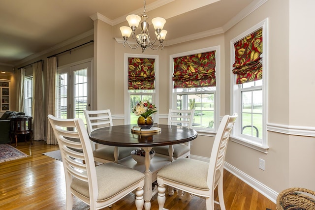 dining area featuring hardwood / wood-style flooring, ornamental molding, and a notable chandelier