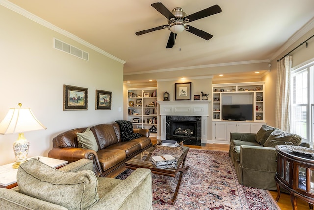 living room with crown molding, hardwood / wood-style floors, built in shelves, and a fireplace