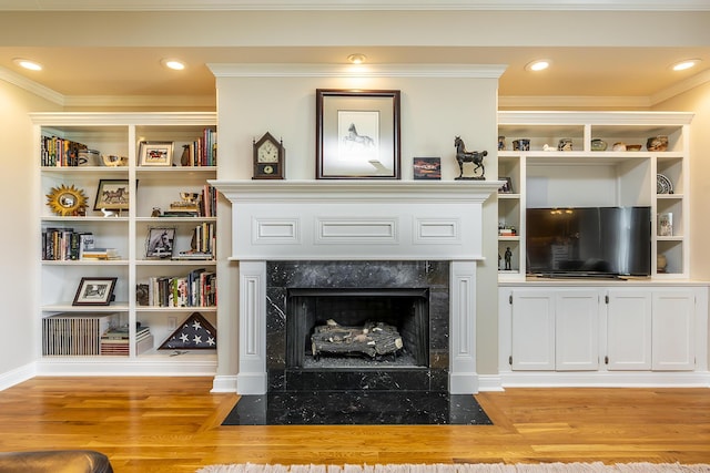 living room with crown molding, light hardwood / wood-style flooring, and a premium fireplace