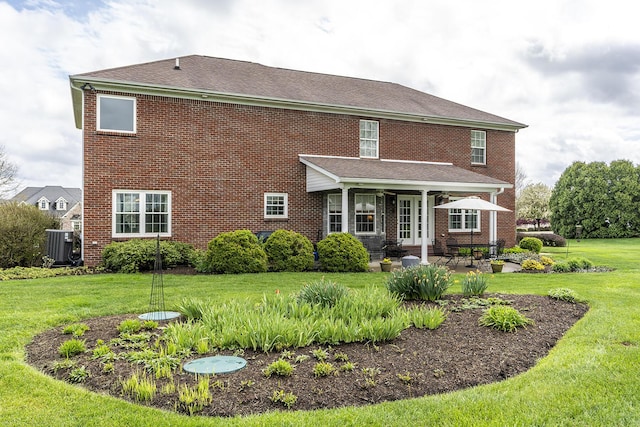 rear view of property with a yard, central AC unit, and a patio