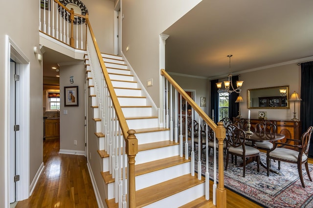 stairway with crown molding, wood-type flooring, and a chandelier