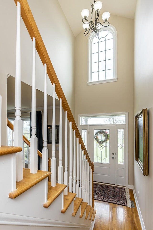 entryway with hardwood / wood-style flooring, high vaulted ceiling, and a chandelier