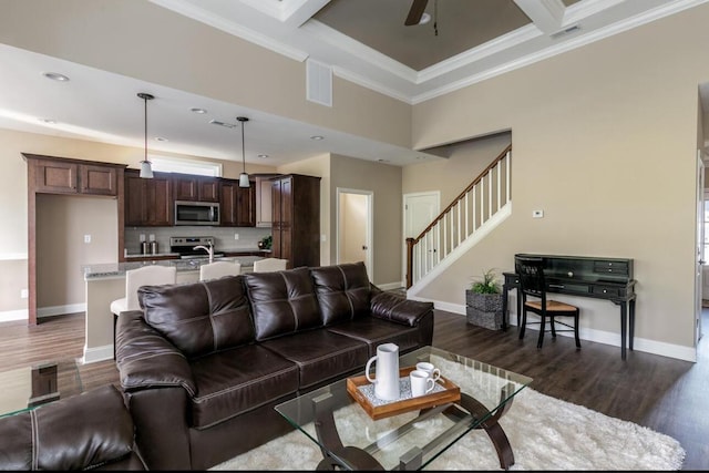 living room featuring ceiling fan, dark hardwood / wood-style floors, coffered ceiling, ornamental molding, and beamed ceiling