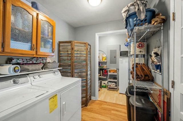 laundry room featuring cabinets, light wood-type flooring, electric panel, and independent washer and dryer