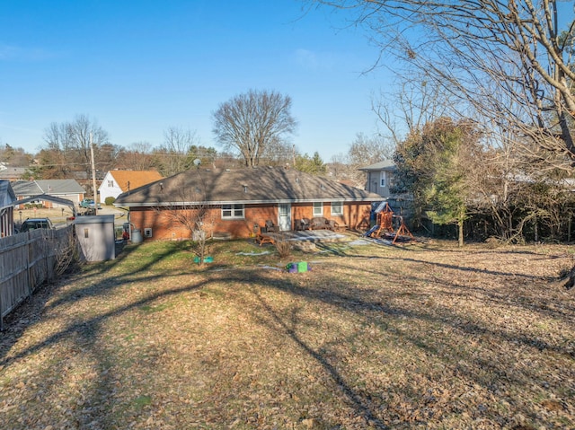 back of property featuring a playground and a lawn