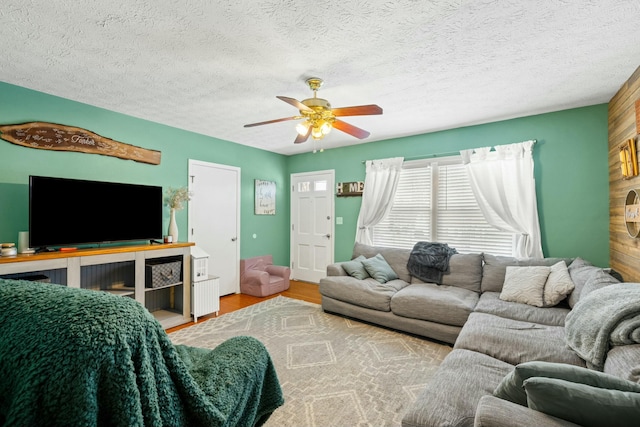 living room with ceiling fan, a textured ceiling, and light hardwood / wood-style floors