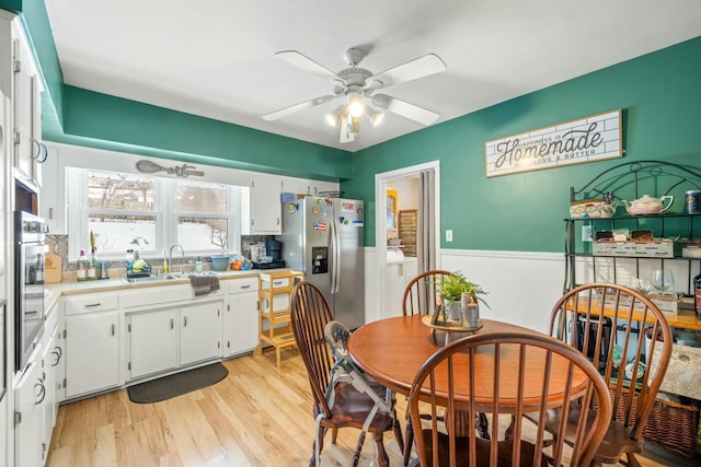 dining area with sink, light hardwood / wood-style flooring, and ceiling fan