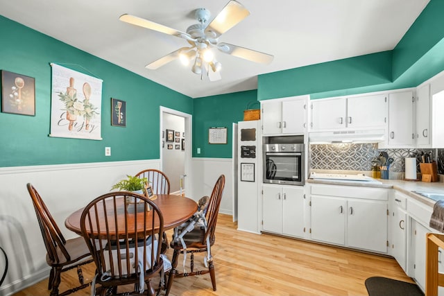 kitchen featuring light hardwood / wood-style flooring, ceiling fan, oven, white cabinets, and cooktop